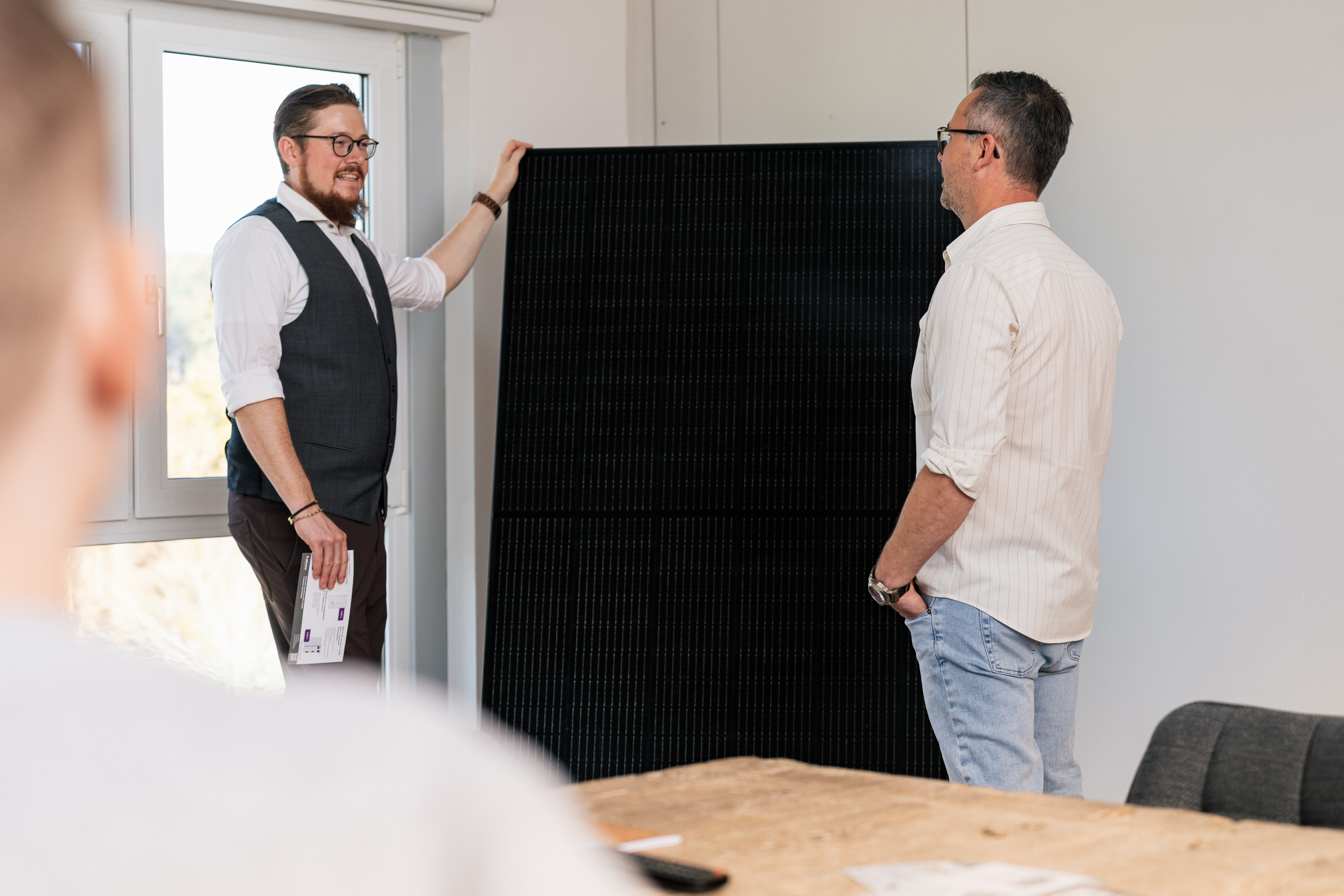Zwei Personen stehen vor einem Solarmodul und unterhalten sich