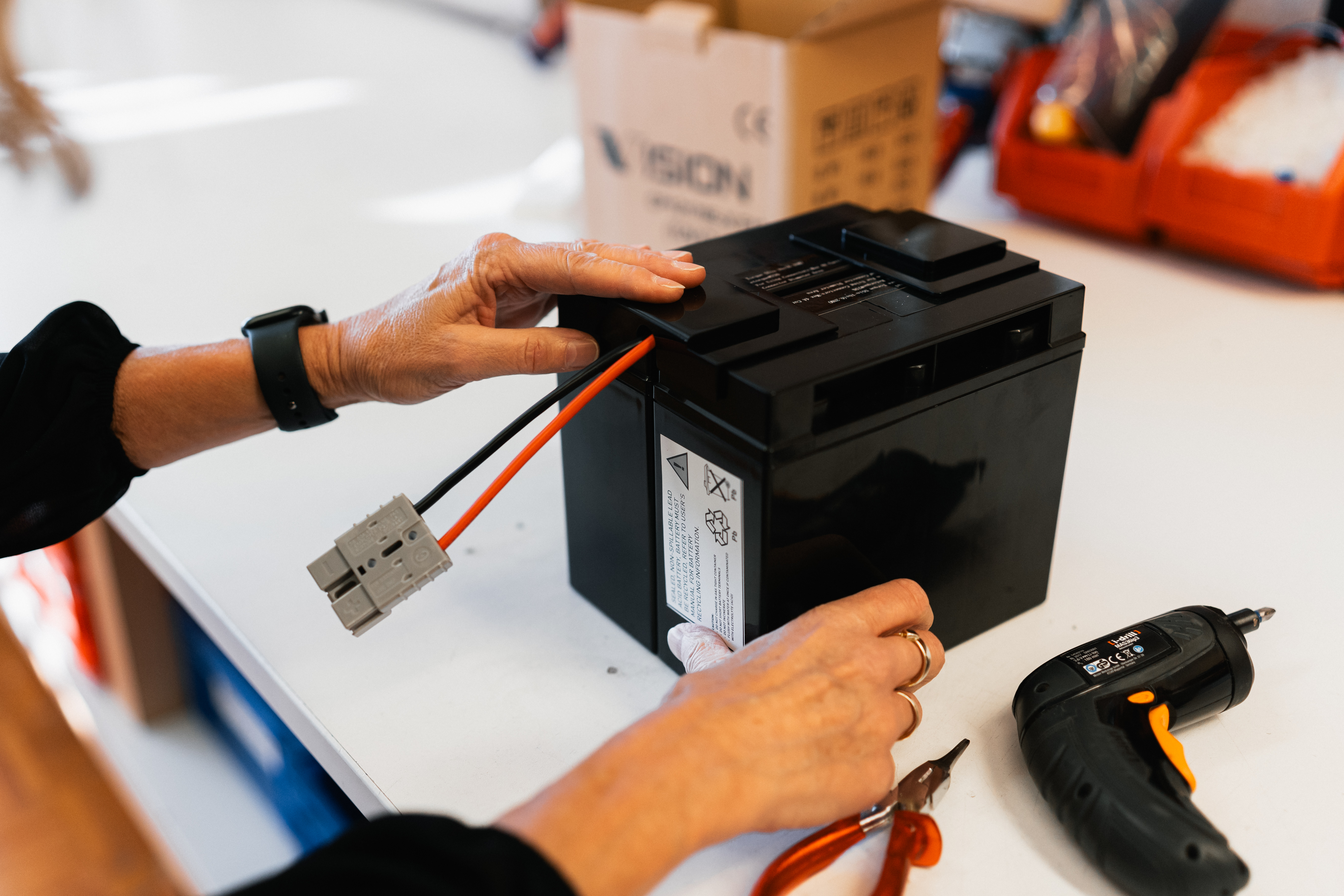 Abbildung einer Batterie die von einer Person bearbeitet wird
